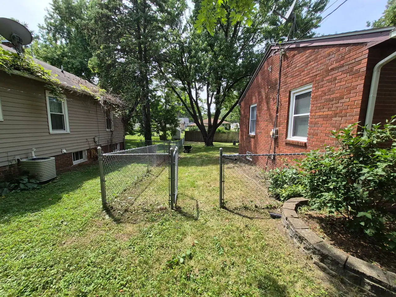 Des Moines backyard cleared of overgrowth and mowed, seen from the back fence